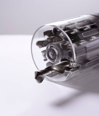 Yuvarlak şeffaf bir çantadaki matkaplar, gri arka plan, inşaat ve onarım konsepti