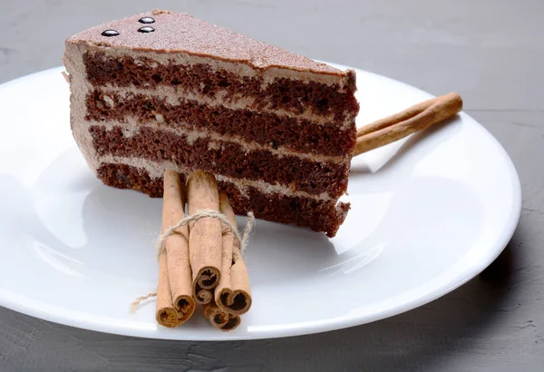 Un morceau de gâteau au chocolat sur un plateau blanc et des rouleaux de cannelle. concept vacances, anniversaire, noël. — Photo