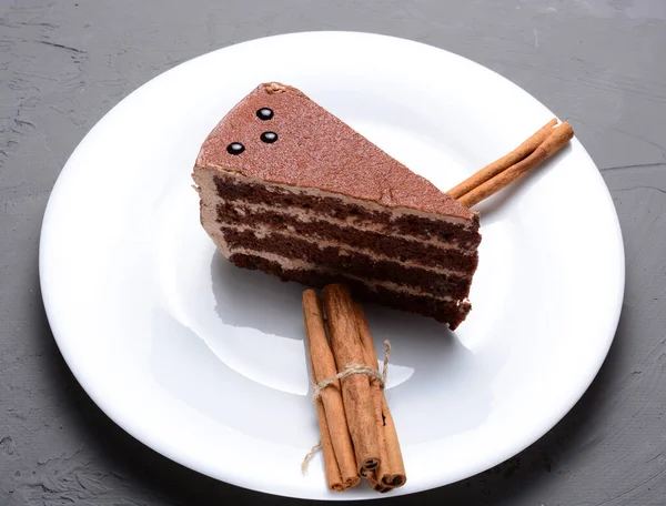 Um pedaço de bolo de chocolate em uma bandeja branca e rolos de canela. conceito de férias, aniversário, natal. — Fotografia de Stock
