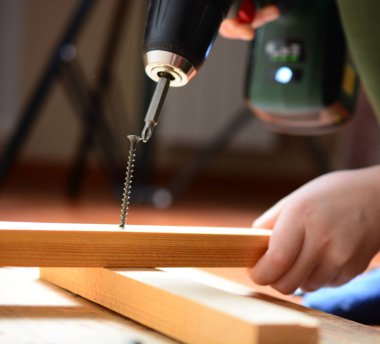 Çocuk kendini pompalayan vidayı elektrikli tornavidayla beceriyor. Ev yenileme konsepti, babama yardım etmek, kendin yapmak, büyümek. yakın plan.