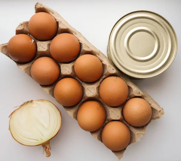 half an onion, a dozen eggs and a tin can of stew on a white background. Donation concept. top view. flat lay.