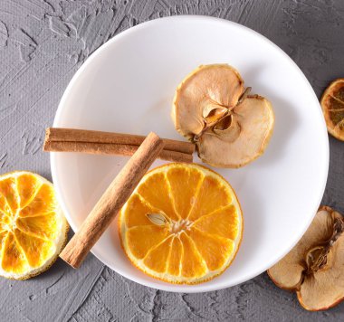Gri ahşap arka planda kurutulmuş portakal, elma ve tarçın dilimleri. Yeni yıl ve Noel 'le tanışma konsepti. Boşluğu kopyala.
