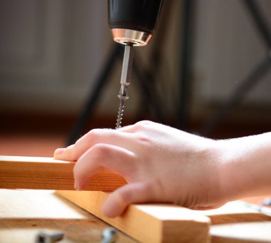 Çocuk kendini pompalayan vidayı elektrikli tornavidayla beceriyor. Ev yenileme konsepti, babama yardım etmek, kendin yapmak, büyümek. yakın plan.