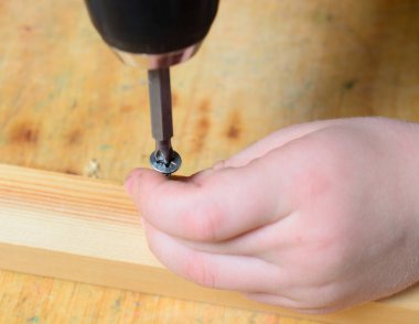 Çocuk kendini pompalayan vidayı elektrikli tornavidayla beceriyor. Ev yenileme konsepti, babama yardım etmek, kendin yapmak, büyümek. yakın plan.