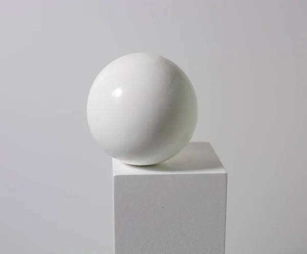 white ball on a white cube, on a white background. beauty minimalism concept, drawing lessons. copy space.