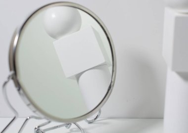 Geometrik şekillerin yuvarlak bir aynasında yansıyor, beyaz bir kübün üzerinde beyaz bir top, beyaz bir silindir üzerinde. Güzellik minimalizmi, çizim dersleri. Boşluğu kopyala