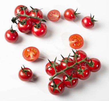 Bir dalda parlak kırmızı kiraz domatesleri ve beyaz masa arkasında tek başına. Boşluğu kopyala.