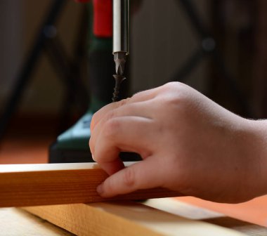 Çocuk kendini pompalayan vidayı elektrikli tornavidayla beceriyor. Ev yenileme konsepti, babama yardım etmek, kendin yapmak, büyümek. yakın plan.