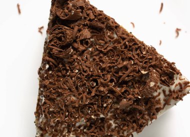 Üzerine rendelenmiş çikolata serpiştirilmiş beyaz bir pasta. Doğum günü tatili, tatlı. Beyaz arka plan. kopyalama alanı. düz yat