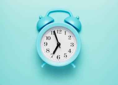 Mavi alarmlı saat okları yediye beş kala. Kalkma, okula gitme ya da çalışma zamanı. Boşluğu kopyala.