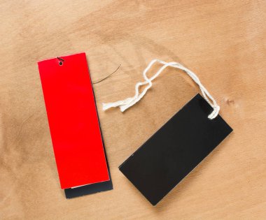 Ahşap arka planda siyah ve kırmızı etiketler yakın plan. Model modeli. Boşluğu kopyala.