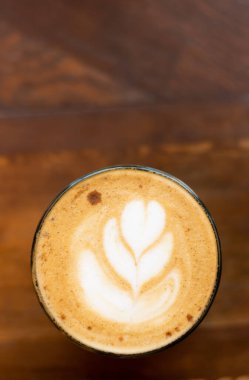 Kahve köpüğüne çizim, ahşap masa arkasına kahve fincanı. Boşluğu kopyala.