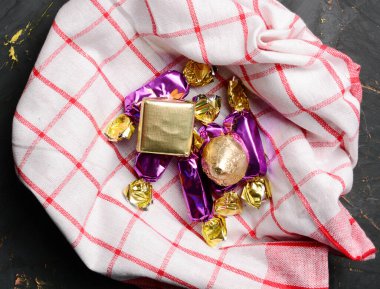 Masa örtüsü üzerinde çeşitli çikolatalar ve parlak bir ambalaj kağıdı. tatil ve doğum günü konsepti. Boşluğu kopyala.