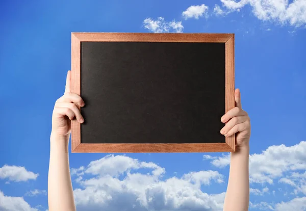 Garçon tenant un cadre avec un fond noir avec place pour le texte. fond ciel bleu avec nuages — Photo