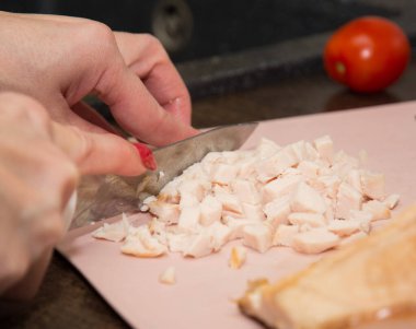 Seçici odaklanma. Kadın haşlanmış tavuk göğsünü küçük parçalara ayırıyor. Ev yapımı pizza pişirme konsepti.