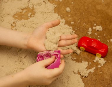 Küçük çocuk kinetik kum ve oyuncaklarla oynuyor. Çocuğun duyusal deneyimleri, mutlu bir çocukluk..