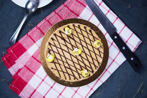 honey cake with edible bees on top on a checkered red towel. concept for birthday, meeting with parents, holidays. flat lay.