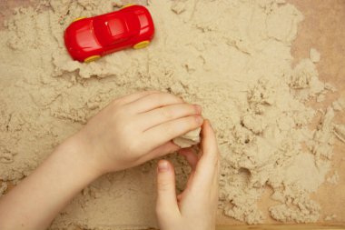 Küçük çocuk kinetik kum ve oyuncaklarla oynuyor. Çocuğun duyusal deneyimleri, mutlu bir çocukluk. Boşluğu kopyala.