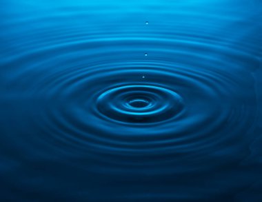 Düşen bir damladan mavi suya dalgalar. Boşluğu kopyala