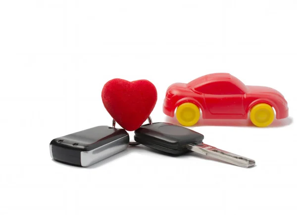 stock image car keys and red heart on the background of a red model car. concept of an expensive gift present to your beloved. white background.
