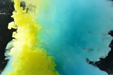 Sarı ve mavi renkler suda birbirine dolanır. Siyah arkaplan.