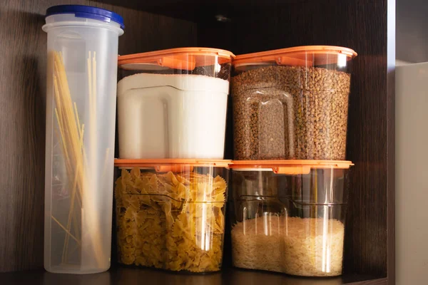 Armario de la cocina con productos pasta, trigo sarraceno, arroz y azúcar. Organización y almacenamiento en la cocina de un armario con grano en recipientes de plástico. — Foto de Stock