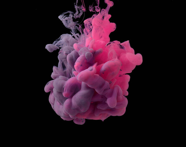 Pink and purple acrylic paints are mixed in clubs and dissolves in water. Black background. copy space.