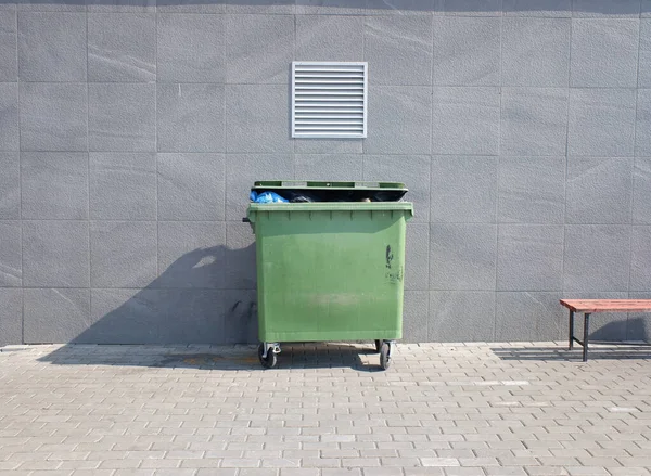 trash container on a background of a gray wall, next to a bench. cleanliness and order minimalism. copy space.