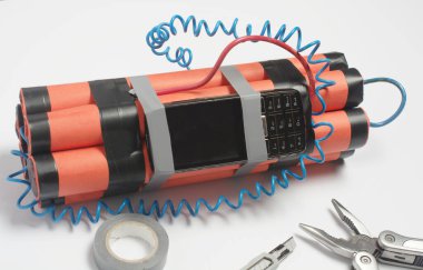 Bir bomba, bir kablo aleti ve eski bir cep telefonu patlamadan önce zamanlayıcı olarak beyaz bir masaya monte ediliyor. Terörizm ve kiralık katil kavramı. Boşluğu kopyala.