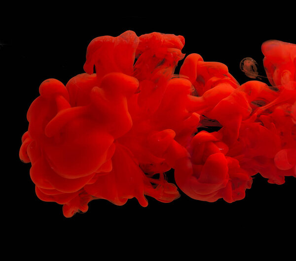 Explosion of acrylic red paint in clear water. Black background. copy space.