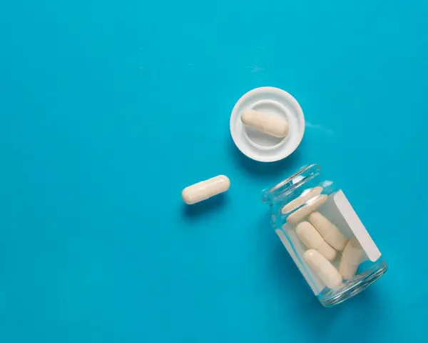 Bílé Kapsle Pilulky Skleněné Sklenice Modré Pozadí Koncepce Léčby Prevence — Stock fotografie