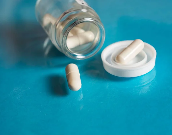 Bílé Kapsle Pilulky Skleněné Sklenice Modré Pozadí Koncepce Léčby Prevence — Stock fotografie
