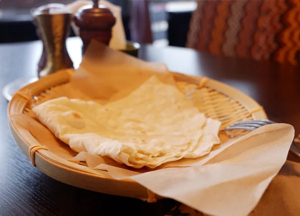 Selektiver Fokus, Fladenbrot auf einem Tablett auf einer Papierserviette in einem Restaurant. vor dem Hintergrund von Gewürzen und dem Blick aus dem Fenster. — Stockfoto