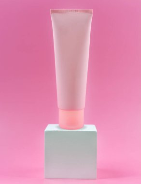 Beyaz küpte kremalı pembe tüp, pembe arka plan. Boşluğu kopyala.