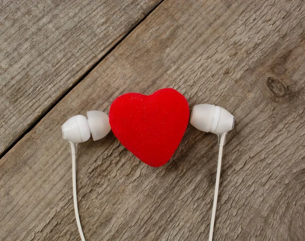 Kulaklıklı kırmızı kalp, tahta arka planda fotokopi alanı var. Çift kavramı, sevgili, müzik, melodi, rahatlama, romantizm ve sevgililer günü. Düz çizgi.