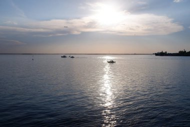 Geniş bir nehrin arka planında batan akşam güneşi. Boşluğu kopyala.