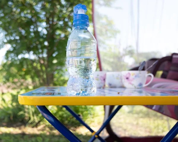 Liten plastflaska med vatten på bordet. Friluftskoncept — Stockfoto