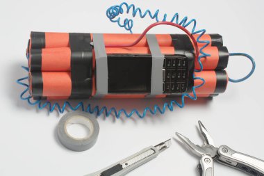 Bir bomba, bir kablo aleti ve eski bir cep telefonu patlamadan önce zamanlayıcı olarak beyaz bir masaya monte ediliyor. Güvenlik ve terörle mücadele kavramı