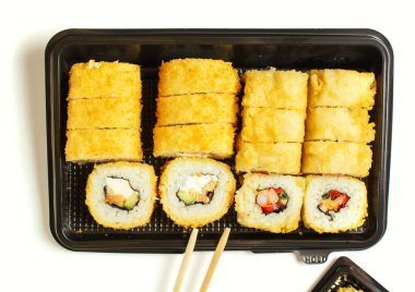 Suşi, iki çubukla birlikte açık siyah bir plastik torbada. Beyaz arka plan. Boşluğu kopyala.