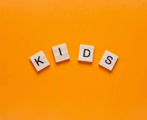 Dzieci Słowo Wykonane Małych Drewnianych Kostek Pomarańczowym Tle Płaskowyż — Zdjęcie stockowe