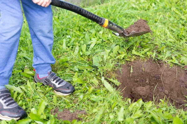 Garçon creuse un trou pour planter un arbre sur le site d'une maison de campagne. vacances à la campagne — Photo