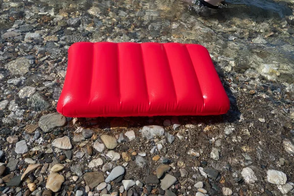 Червоний надувний гумовий матрац на пляжі на гальковому березі. відпустка і відпочинок на морі — стокове фото