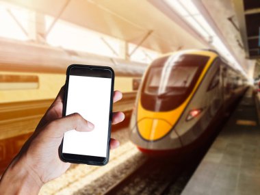 Modern trenin önünde boş ekranlı siyah akıllı telefonu olan bir adam tren istasyonuna doğru ilerliyor. Metin veya tasarım için boşluk