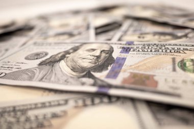 Masada yığınla dolar var. 100 dolarlık banknotlar masaya dökülüyor. Çok paradan tasarım için arka plan. Bulanık odak. Yakın plan. Yan görünüm