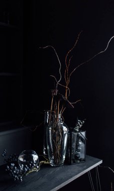 Modern, güzel, koyu renk iç mekan, oda grisi renk, gardırop rafları alışılmadık kasvetli dekorasyon masası kumaşı, kurutulmuş çiçekler, su dolu vazolar, yosun, dallar, alışılmadık bir tarz, cadılar bayramı.