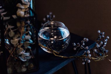 Modern, güzel, koyu renk iç mekan, oda grisi renk, gardırop rafları alışılmadık kasvetli dekorasyon masası kumaşı, kurutulmuş çiçekler, su dolu vazolar, yosun, dallar, alışılmadık bir tarz, cadılar bayramı.