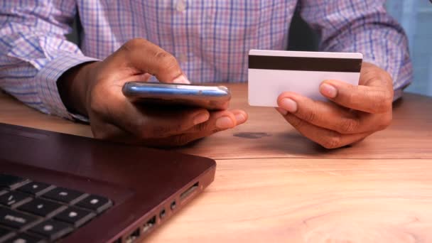Adamın biri kredi kartını tutuyor ve online akıllı telefon alışverişi yapıyor. — Stok video