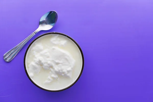 Закрытие свежего йогурта в миске на цветном фоне — стоковое фото