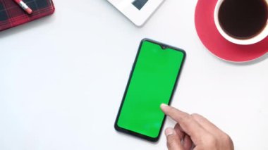 Ofis masasında akıllı telefon kullanan bir adamın üst görüntüsü. 