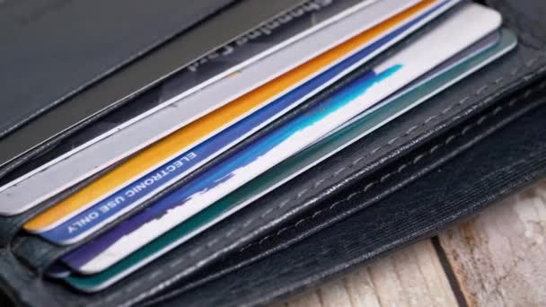 Close-up de cartões de crédito em uma carteira em fundo de madeira — Vídeo de Stock